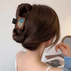 Vue détaillée d'une pince à cheveux en cuir style western avec motif plume sur cheveux.