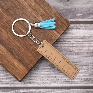 Detailed shot of wooden ruler keychain with blue tassel and engraved teacher message