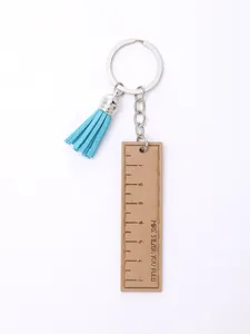 Detailed view of a wooden ruler keychain with a blue tassel and 'Mrs. Silzer, You Rule!' text