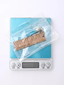 Wooden ruler keychain with blue tassel shown weighing 8.8g on a digital scale