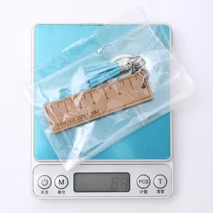 Wooden ruler keychain with blue tassel weighing 8.8g on a silver digital scale