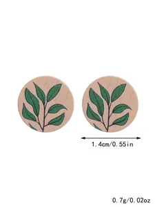 Detailed view of circular wooden stud earrings with leaf pattern showing size and weight