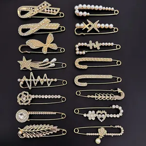 Collection of diverse decorative safety pins with rhinestones and pearls on black background