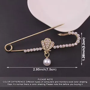 Detailed macro view of a gold shell pearl safety pin brooch with size measurements