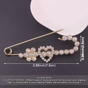 Detailed view of heart-shaped rhinestone safety pin brooch with size labels 7.5cm x 2.5cm