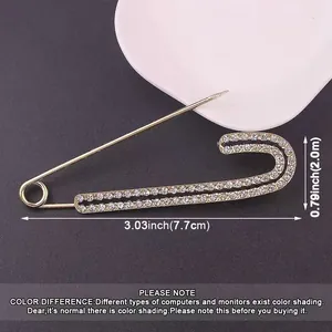 Close-up of gold rhinestone safety pin brooch with dimension measurements