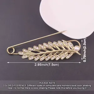 Close-up of golden leaf safety pin brooch with rhinestones and pearl details