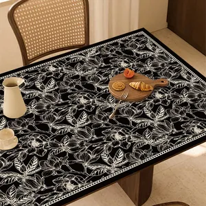 Dettaglio di tovaglia in pelle nera con elegante motivo floreale a linee bianche