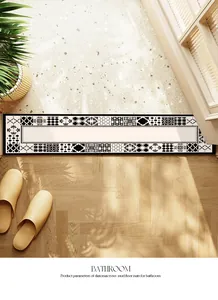 Détail d'un tapis de bain à motif géométrique noir et blanc sur sol en bois.