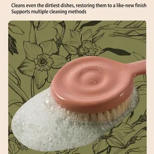 Pink kitchen cleaning brush with dense bristles and handle shown in rich white soapy foam