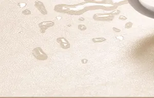 Vue macro de la surface de la nappe en cuir beige imperméable avec gouttes d'eau.