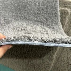 Macro detail of thick grey plush shag rug showing absorbent pile and edge binding