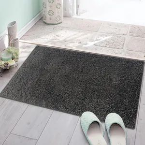 Detail view of a thick dark grey plush bath mat placed at a bright modern house doorway