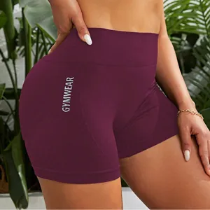 Detailansicht der weinroten nahtlosen Fitness-Shorts mit weißem GYMWEAR-Aufdruck
