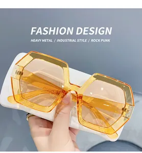 Close-up of oversized polygonal sunglasses with amber gradient lenses and irregular frames