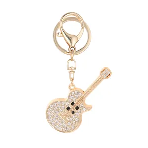 Elegant gold metal guitar keychain featuring sparkling rhinestone decorations for bags