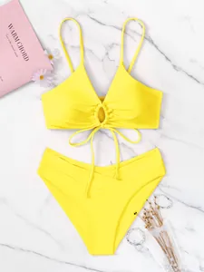 Vista dettagliata di alta qualità di un bikini giallo a due pezzi con anello frontale su marmo