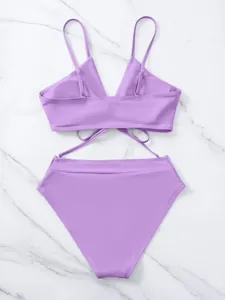 Set bikini viola a vita alta con dettaglio stringato sul retro su sfondo marmo.