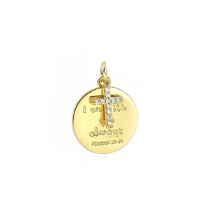 Detalle de un colgante redondo bañado en oro con cruz de circón y grabado religioso