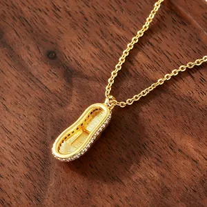 Gold-plated sneaker pendant necklace with sparkling zirconia on dark wood background