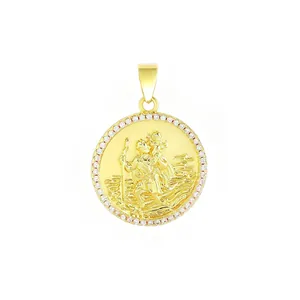 Primer plano de un colgante redondo chapado en oro con figura religiosa y circonitas.