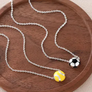 Silver-plated sports necklace set with soccer and yellow softball ball pendants on wood