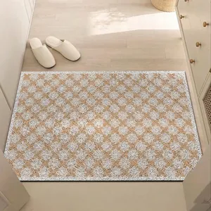 Detail view of a brown and white geometric silk loop doormat on a wooden floor.