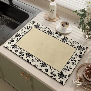 Detailed view of an absorbent kitchen mat with elegant black floral borders.