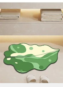 Alfombra de baño absorbente con forma de hoja verde sobre suelo claro con zapatillas