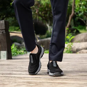 Macro view of men's black waterproof outdoor sports shoes worn on a wooden park walkway