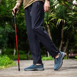 Men wearing blue outdoor sports shoes with trekking pole on wooden path detail view