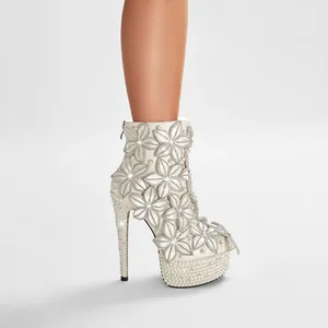 Vista detallada de botines blancos de novia con pedrería floral y elegantes perlas finas