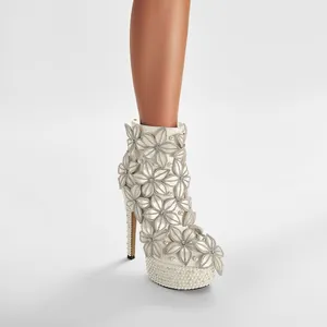 Detalle de botines de novia blancos con flores de pedrería y decoración de plataforma