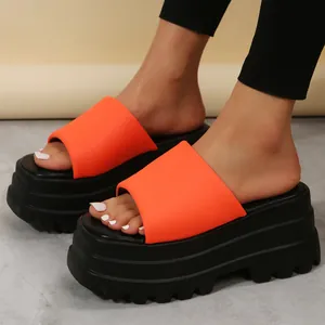 Close-up of stylish bright orange platform wedge slide sandals with thick black lug soles
