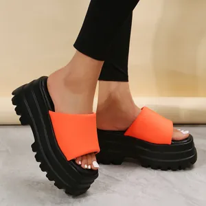 Detailed view of stylish orange platform slides featuring chunky black thick soles.