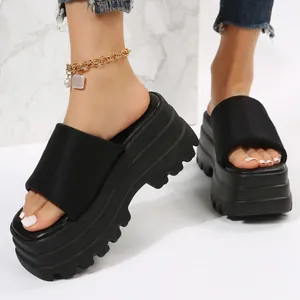 Close-up of stylish black platform slippers with thick serrated sole on model