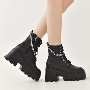 Detalle de botas góticas negras de plataforma con cadenas plateadas y tacón ancho.