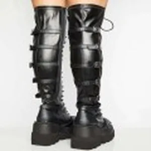 Detail of punk style black over-the-knee boots with multiple decorative buckle straps