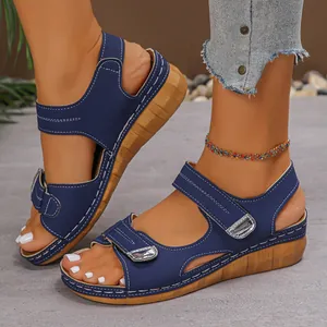 Detailaufnahme von dunkelblauen Damen-Keilsandalen mit Kontrastnähten und Schnallen