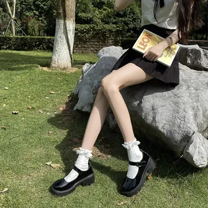 Close-up of black platform Mary Jane shoes with white lace socks in a garden setting