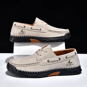 Close-up of beige hand-stitched casual men's loafers with black rubber soles and orange accents