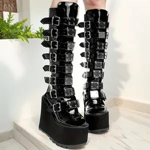 Close-up of black patent leather knee-high boots with 11cm platform and metal buckles