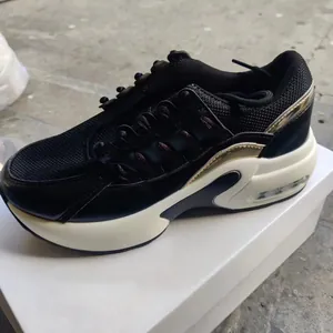 Perfil lateral de una zapatilla de cuña transpirable en malla negra para mujer en caja