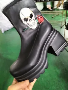 Macro detail view of the skull and rose embroidery on black platform ankle boots