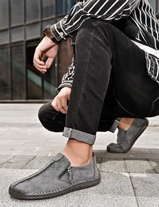 Détail de mocassins en cuir gris pour hommes avec fermeture éclair et coutures main.