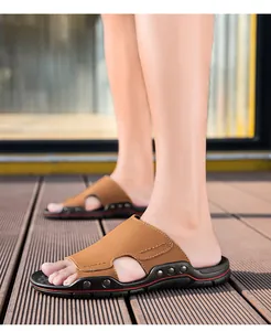 Dettaglio di sandali da uomo in pelle marrone con borchie metalliche e suole nere