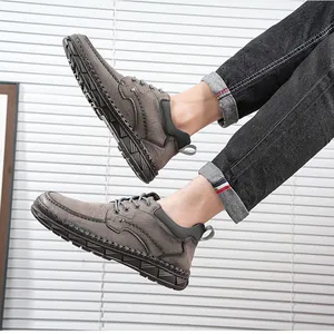 Détails de bottines en cuir gris cousues main pour hommes portées avec un jean noir.
