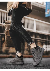 High-angle lifestyle view of grey leather high-top outdoor hiking boots on a male model