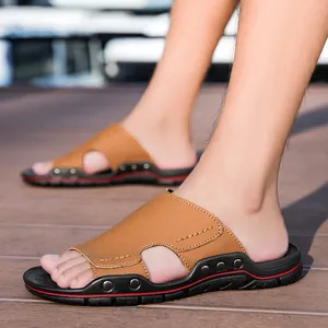 Ciabatte da uomo in pelle marrone con borchie decorative e bordo rosso su pavimenti