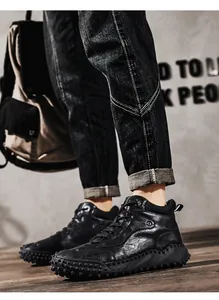 Close-up of black leather high-top outdoor boots with unique rugged anti-slip sole design.